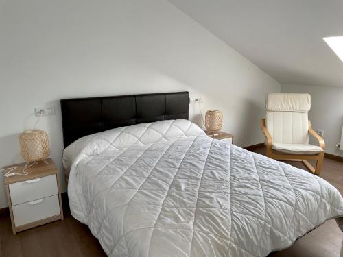 a bedroom with a large white bed and a chair at Alojamientos con encanto Ruliña in Portomarin