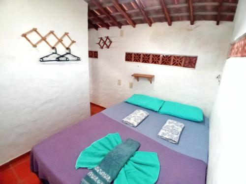 Casa da Lua في جاكوما: غرفة مع سرير مع وسائد خضراء وأرجوانية
