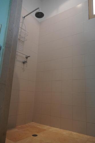 a shower in a bathroom with white tile at Hotel Boutique Villa Casuarinas in Cali