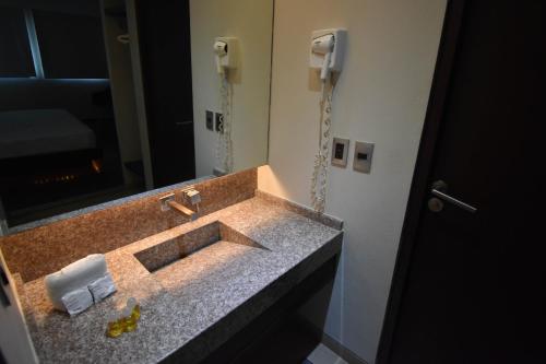 a bathroom with a sink with a mirror and a phone at Hotel Via La Villa in Mexico City