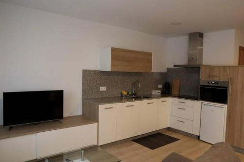 Il comprend une cuisine avec des placards blancs et une télévision à écran plat. dans l'établissement Apartamento CATA Santiago de Compostela, à Saint-Jacques-de-Compostelle