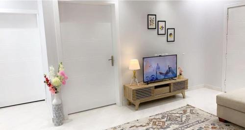 una sala de estar con TV y un jarrón de flores en مساكن الدار 1 en Abha