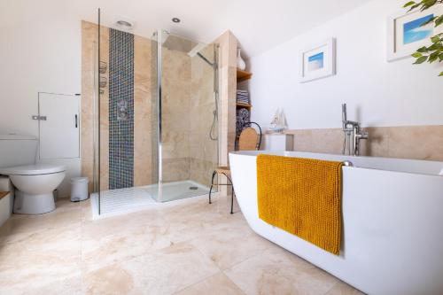 a bathroom with a shower and a tub and a toilet at Central Penzance, Modern stylish home, Near Seafront with Gated parking in Penzance
