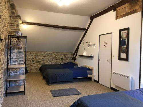 1 dormitorio con 2 camas en una habitación con pared de piedra en Le Gîte du Lotus Corrézien, en Le Lonzac