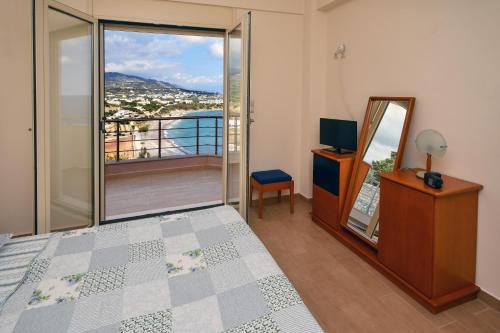 a bedroom with a bed and a television and a balcony at Villa Blue Dream in Koutsounari