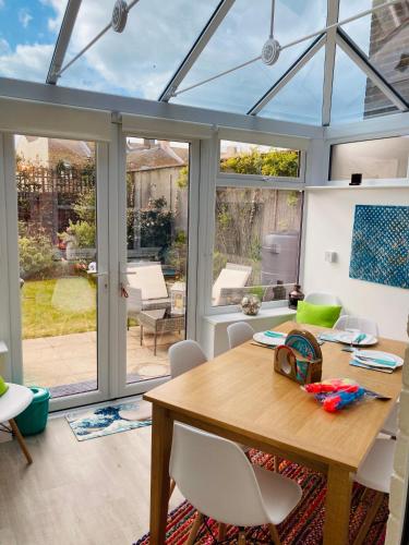 a conservatory extension with a wooden table and chairs at Stunning Seafront House with garden and private parking in Eastbourne