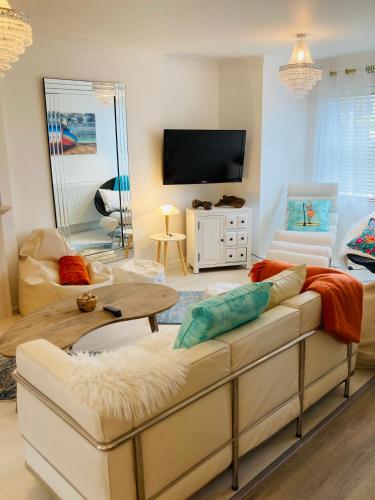 a living room with a couch and a tv at Stunning Seafront House with garden and private parking in Eastbourne