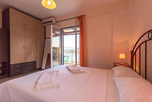 a bedroom with a large white bed with a balcony at Elia Village in Meganisi