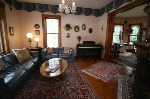 a living room with a couch and a table and a piano at The Governor's Inn in Ludlow