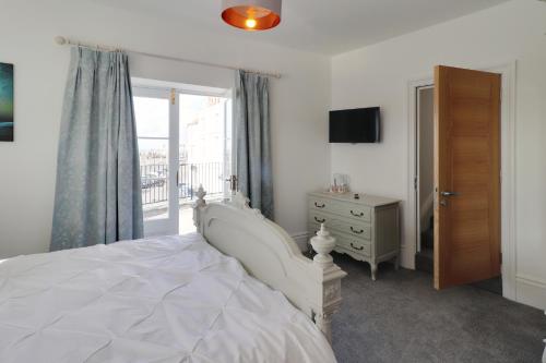 a bedroom with a white bed and a window at Master accommodation suite 2 sea view with balcony in Hastings
