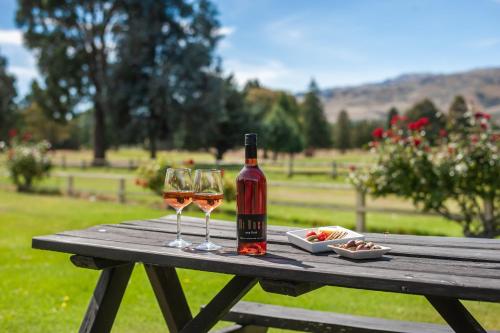 una bottiglia di vino e due bicchieri su un tavolo da picnic di Lake Dunstan Motel a Cromwell