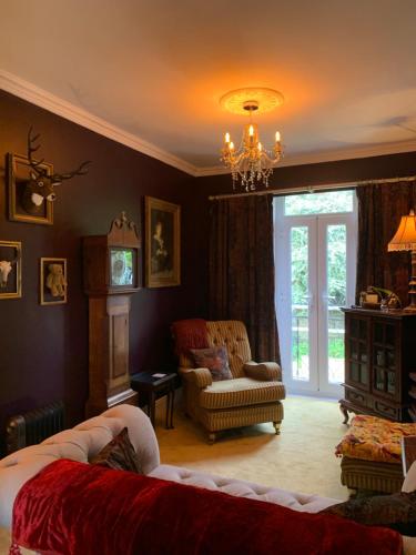 a living room with a couch and a chair and a chandelier at The Attic Apartment at Number 54 in Ilfracombe