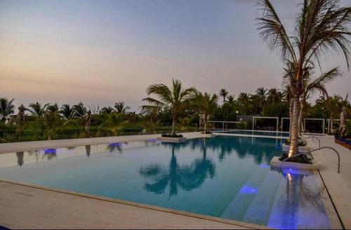 a large swimming pool with palm trees in a resort at Cartagena Morros ío, apto sol nuevo frente al Mar Serena Del Mar in Cartagena de Indias