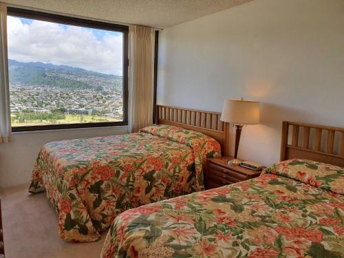 a hotel room with two beds and a large window at PonoAloha in Honolulu