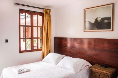 a bedroom with a bed with a wooden headboard and a window at Hotel Los Portales Inn in Popayan