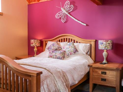a bedroom with a bed with a purple wall at Stable Cottage in Stoupe Brow