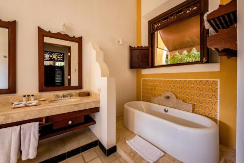 a bathroom with a tub and a sink and a mirror at Hacienda San Antonio Millet in Tixkokob