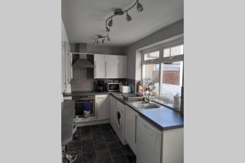 a kitchen with white cabinets and a sink and a window at Seaside Home from Home 4bedroom sleeps 8 in Bridlington