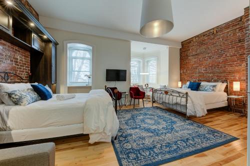 a bedroom with two beds and a brick wall at Le 555 Hébergements touristiques in Quebec City