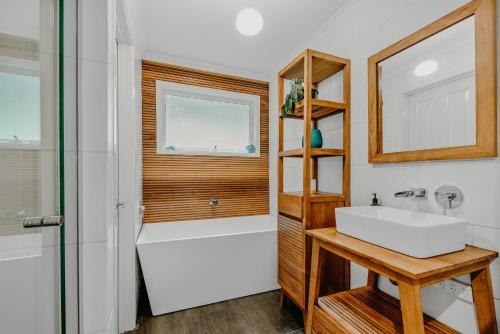 a bathroom with a tub and a sink and a mirror at Steep Creek Retreat in Belgrave