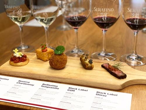 a wooden cutting board with wine glasses and food at Serafino McLaren Vale in McLaren Vale