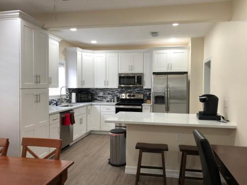 uma cozinha com armários brancos e electrodomésticos de aço inoxidável em Seaside Cottage em Galveston