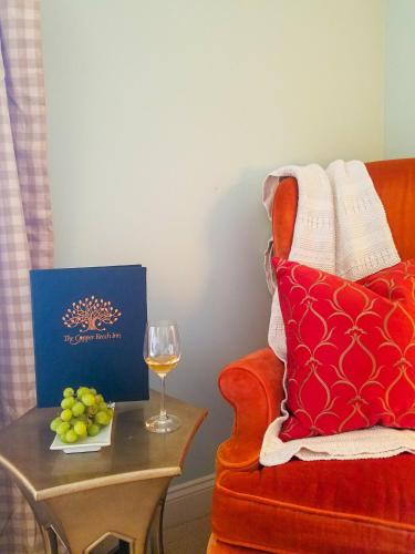 a living room with a chair and a table with a glass of wine at Copper Beech Inn in Ivoryton