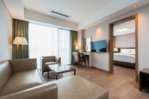 a living room with a couch and a room with a bed at Stanford Hotel&Resort Tongyeong in Tongyeong