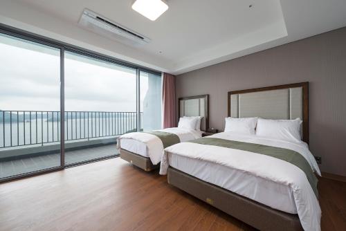 two beds in a hotel room with a large window at Stanford Hotel&Resort Tongyeong in Tongyeong