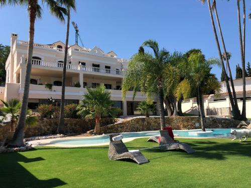 ein Resort mit zwei Stühlen vor einem Pool in der Unterkunft Huge Golf and Spa Mansion 8 min from Puerto Banus in Estepona