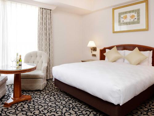a hotel room with a bed and a chair and a table at Sendai Royal Park Hotel in Sendai