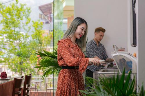 a woman in a red dress standing in a kitchen at Sapa Mountain Queen House in Sapa