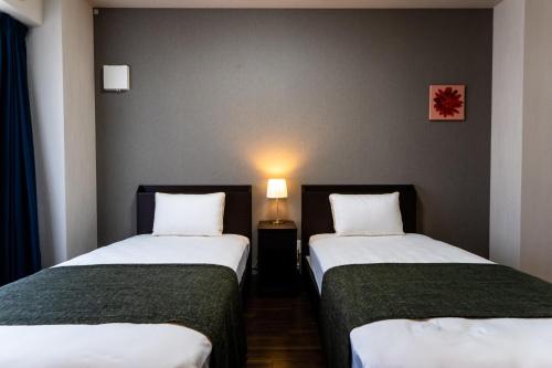 two beds in a small room with a lamp at Hotel Piacere NAMBA in Osaka