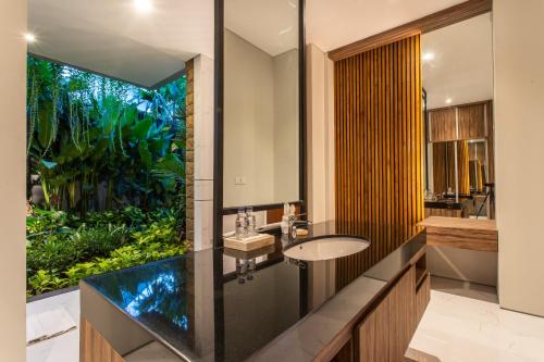 La salle de bains est pourvue d'un lavabo et d'une grande fenêtre. dans l'établissement The Amarta Villa, à Jimbaran