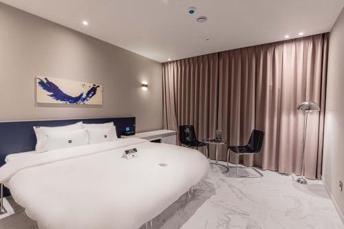 a hotel room with a large white bed and chairs at Zam101 Hotel Gimhae in Gimhae