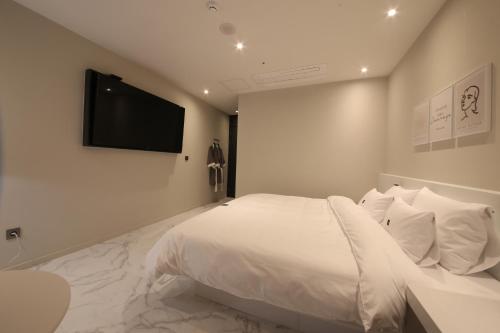 a bedroom with a white bed and a flat screen tv at Zam101 Hotel Gimhae in Gimhae