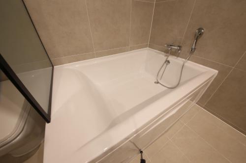 a white bath tub in a bathroom with a shower at Zam101 Hotel Gimhae in Gimhae