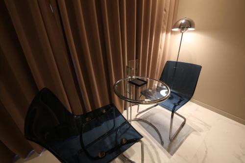 a glass table and a chair and a lamp in a room at Zam101 Hotel Gimhae in Gimhae