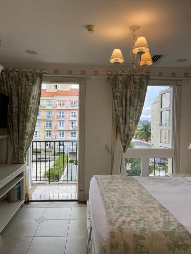 1 dormitorio con cama y ventana grande en Il Campanario - Vista Para a Piscina, en Florianópolis