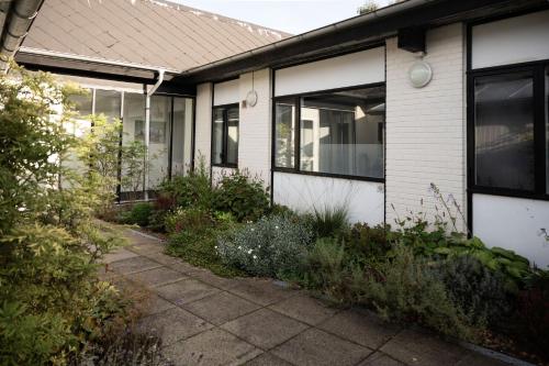 a white house with windows and a sidewalk at Motel Poppelvej in Herning