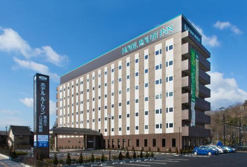 a large building with a white inn sign on it at Hotel Route-Inn Higashiomi Yokaichi Ekimae in Yōkaichi