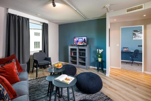 a living room with a couch and a tv at Hotel Welcome Inn in Kloten