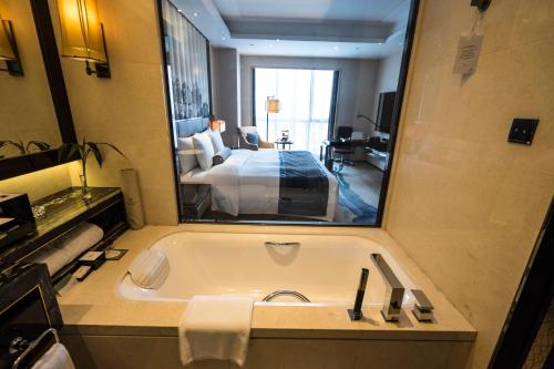 a bathroom with a bath tub and a bedroom at Wanda Realm Jining in Jining