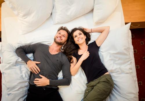 a man and a woman laying on a bed at Hotel Jager Hans in San Martino