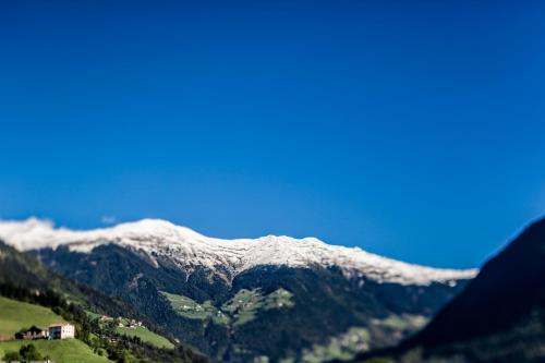 a snow covered mountain range with a house in the foreground at Hotel Jager Hans in San Martino