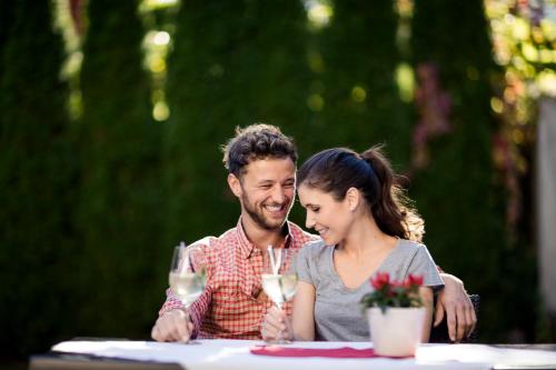 a man and a woman sitting at a table with wine glasses at Hotel Jager Hans in San Martino