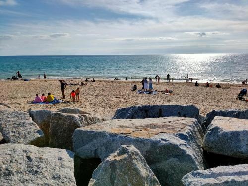 eine Gruppe von Menschen am Strand mit Felsen in der Unterkunft Les sables d'or in Agon Coutainville