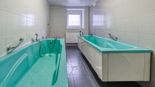 y baño con bañera azul y lavamanos. en Kaja Medical & Spa, en Świeradów-Zdrój