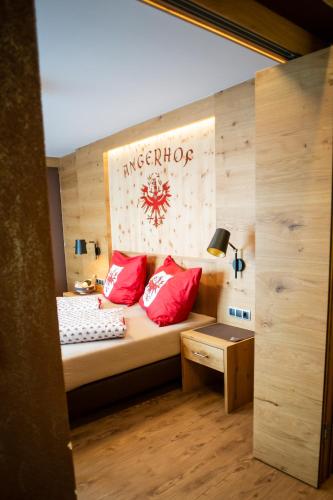 a small room with a bed with red pillows at Ferienhotel Angerhof in Fiss