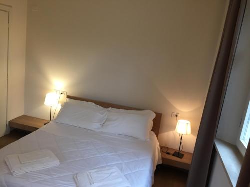 a bedroom with a white bed with two lamps at Ceccarini Suite in Riccione